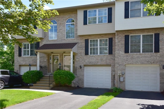 multi unit property featuring an attached garage, driveway, and brick siding