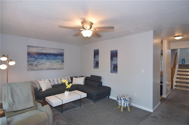 carpeted living area with a ceiling fan, baseboards, and stairs