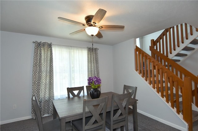 dining area featuring stairs, carpet flooring, a ceiling fan, and baseboards