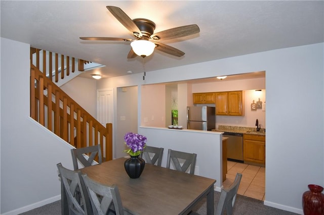 dining area with light colored carpet, ceiling fan, stairway, baseboards, and light tile patterned flooring