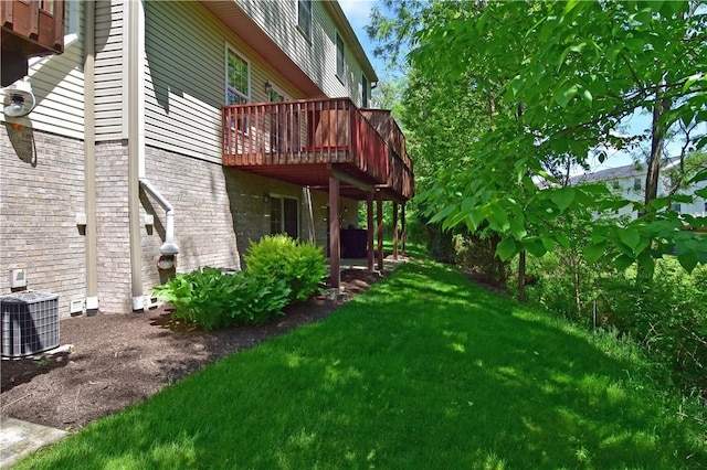 view of green lawn featuring a wooden deck and central AC unit