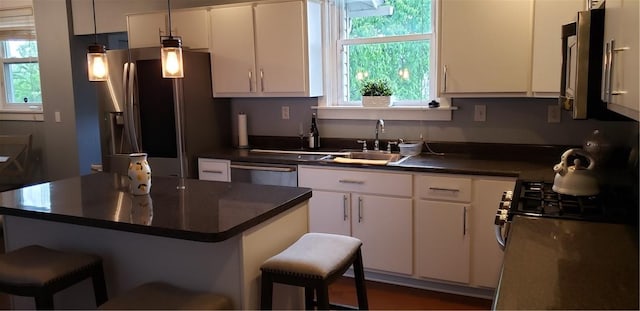 kitchen with appliances with stainless steel finishes, a sink, white cabinets, and dark countertops