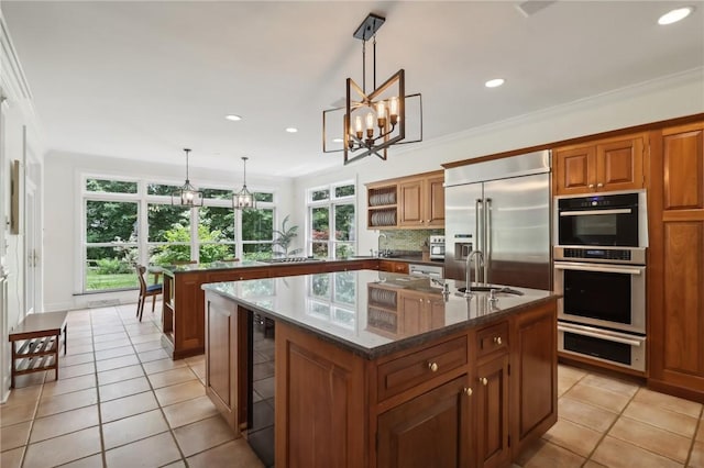 kitchen featuring stainless steel appliances, brown cabinetry, an island with sink, a sink, and recessed lighting