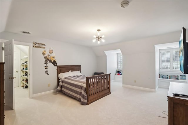 carpeted bedroom with lofted ceiling, baseboards, a chandelier, and a walk in closet