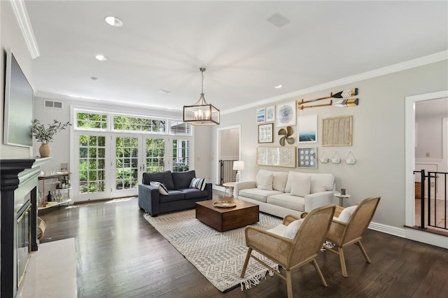 living area featuring ornamental molding, dark wood-type flooring, a chandelier, a premium fireplace, and recessed lighting