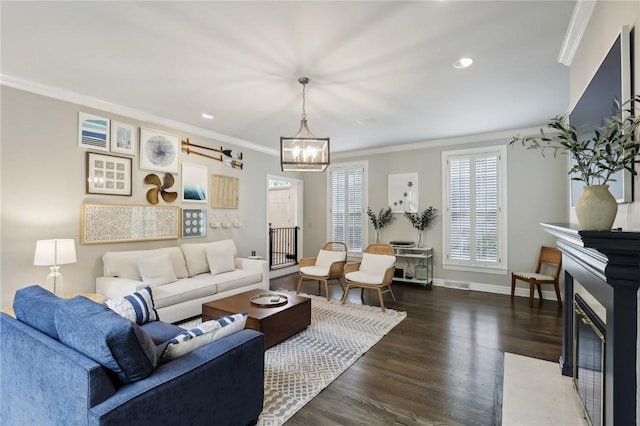 living area with crown molding, wood finished floors, a chandelier, a fireplace, and baseboards