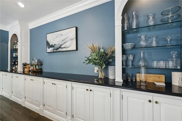 indoor dry bar with crown molding, arched walkways, and dark wood-style flooring