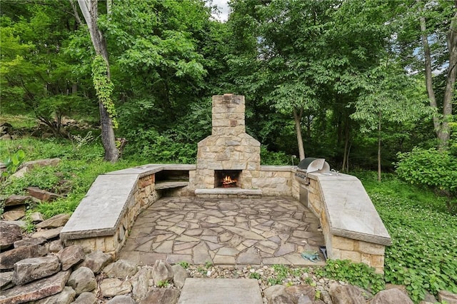 view of patio with an outdoor stone fireplace, grilling area, and an outdoor kitchen