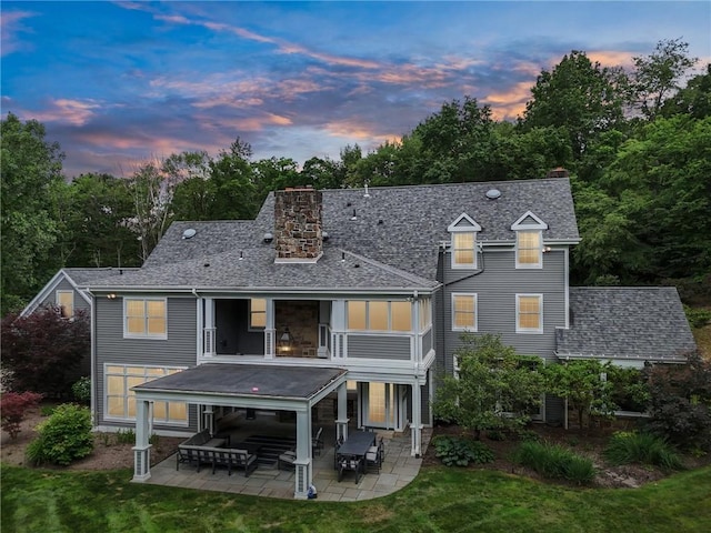 rear view of house with a patio, a chimney, and a shingled roof
