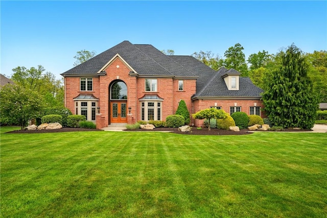 view of front of house with french doors, brick siding, and a front yard