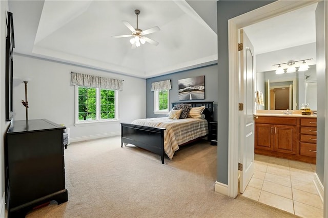 bedroom with light colored carpet, a raised ceiling, a sink, and baseboards