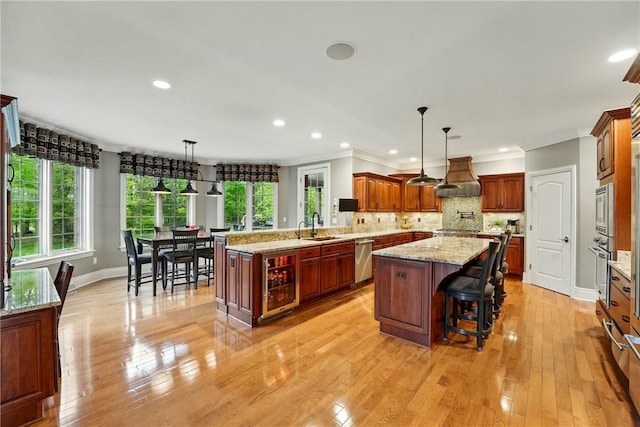 kitchen with beverage cooler, a center island, extractor fan, stainless steel appliances, and recessed lighting