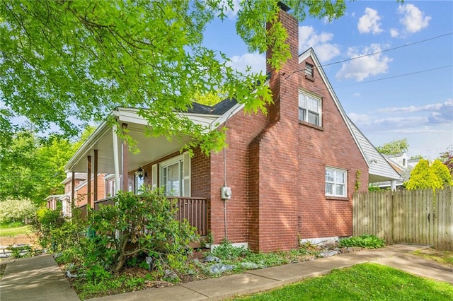 339 Hamil Rd, Penn Hills, PA 15147 - view of side of property with brick siding, a chimney, covered porch, and fence