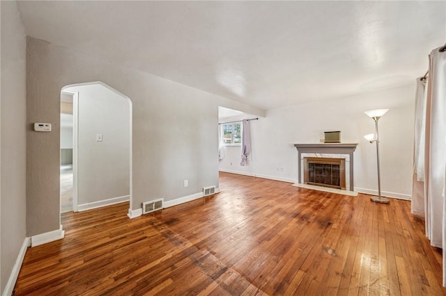 339 Hamil Rd, Penn Hills, PA 15147 - unfurnished living room featuring hardwood / wood-style floors, a glass covered fireplace, baseboards, and arched walkways