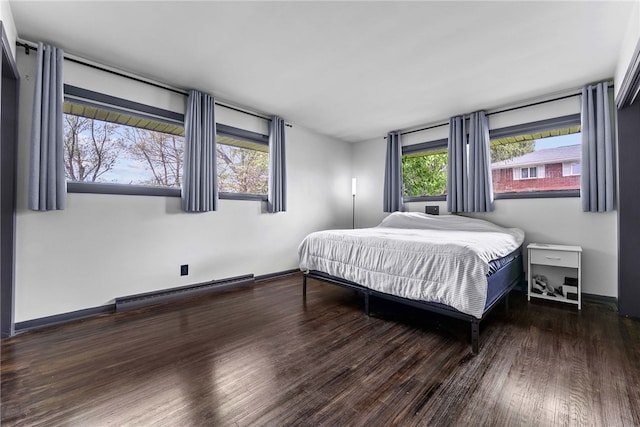 bedroom featuring baseboard heating, wood finished floors, and baseboards