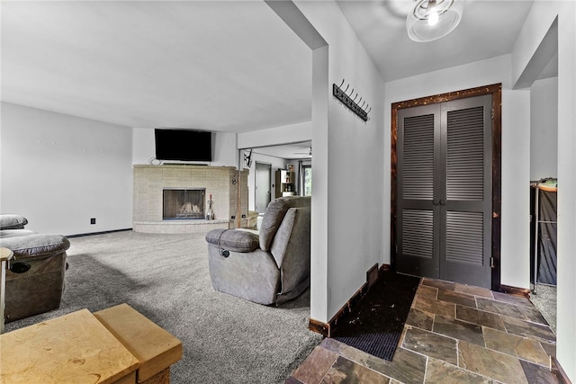 entrance foyer with baseboards, a fireplace, stone finish flooring, and carpet flooring
