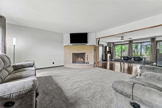 carpeted living room featuring a fireplace, a ceiling fan, and baseboards