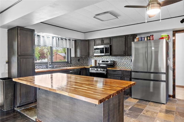 kitchen with butcher block counters, stainless steel appliances, a sink, backsplash, and dark brown cabinets