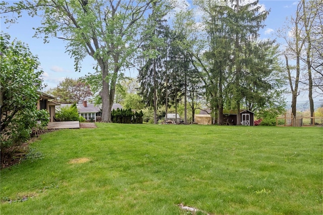 view of grassy yard with a storage unit and an outbuilding