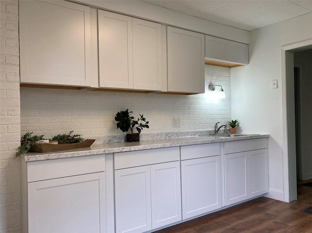 kitchen with backsplash, dark wood-type flooring, light countertops, a sink, and white cabinets