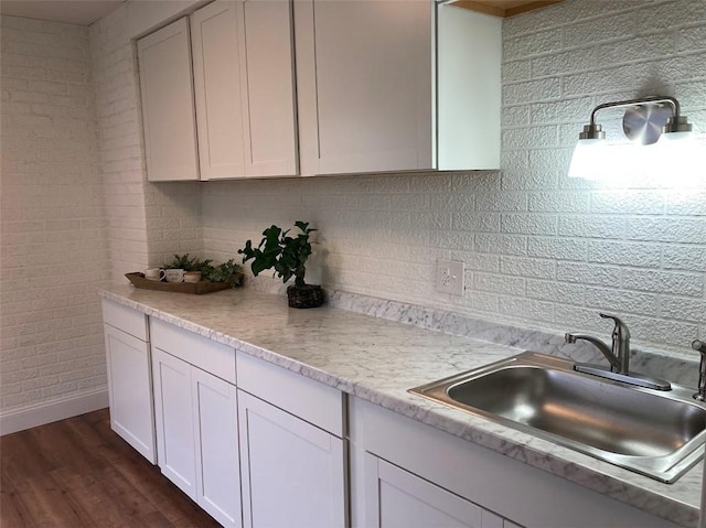 kitchen with a sink, light countertops, tasteful backsplash, dark wood-type flooring, and white cabinetry