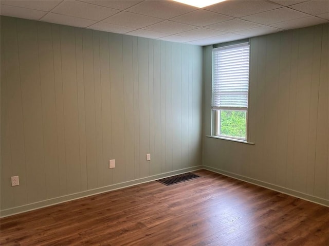 empty room featuring wood finished floors, baseboards, and wood walls