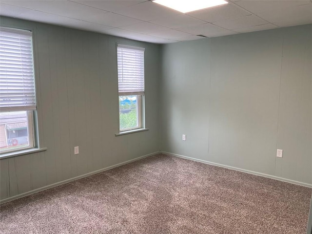empty room with carpet flooring, baseboards, and a drop ceiling