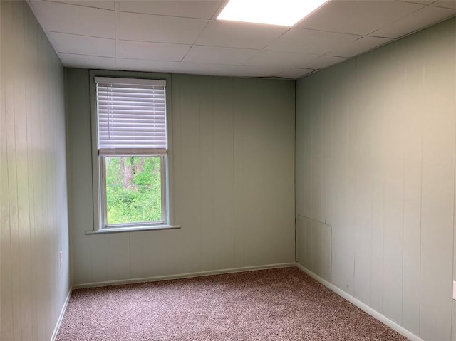 carpeted spare room with a drop ceiling and baseboards