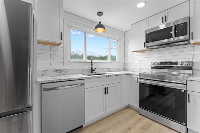 5056 Don St, Finleyville, PA 15332 - kitchen featuring appliances with stainless steel finishes, a sink, light wood-style flooring, backsplash, and white cabinets