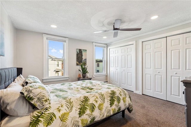 bedroom with carpet, two closets, recessed lighting, a textured ceiling, and a ceiling fan