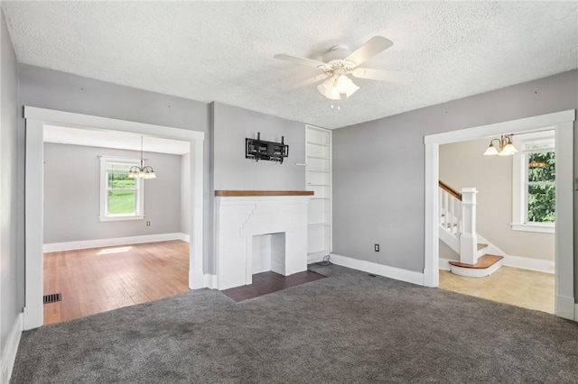 506 7th Ave, Coraopolis, PA 15108 - unfurnished living room with a chandelier, carpet, a textured ceiling, stairway, and a fireplace with flush hearth