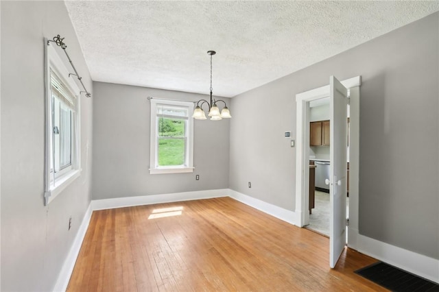 506 7th Ave, Coraopolis, PA 15108 - unfurnished dining area with a textured ceiling, light wood-style flooring, baseboards, and a chandelier