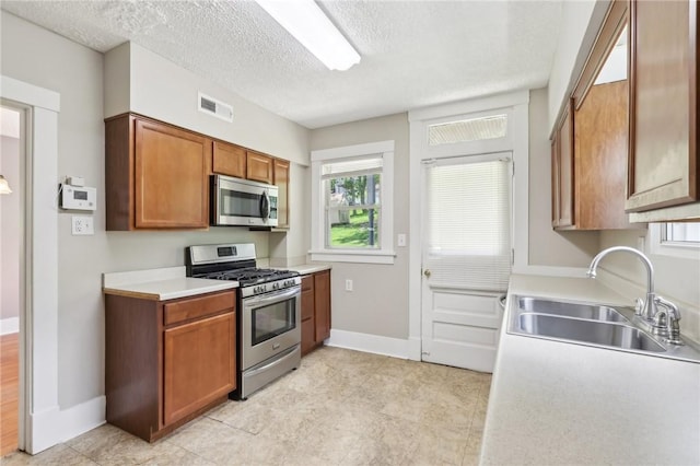 506 7th Ave, Coraopolis, PA 15108 - kitchen featuring appliances with stainless steel finishes, a sink, brown cabinetry, baseboards, and light countertops