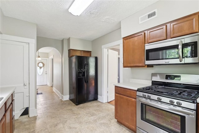 506 7th Ave, Coraopolis, PA 15108 - kitchen with appliances with stainless steel finishes, arched walkways, brown cabinets, light countertops, and a textured ceiling