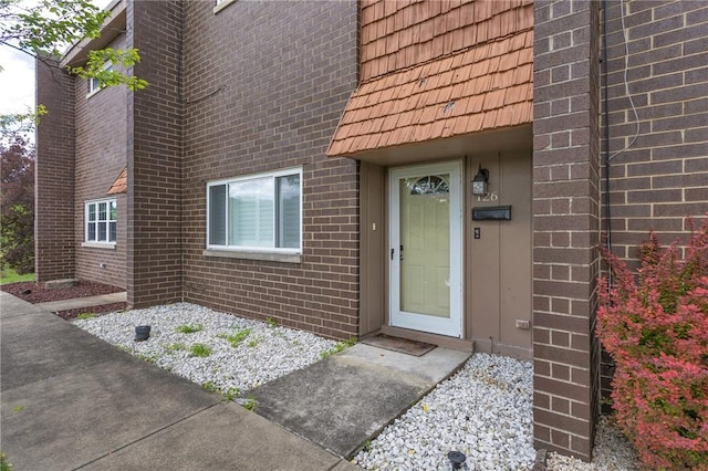 doorway to property with brick siding and mansard roof