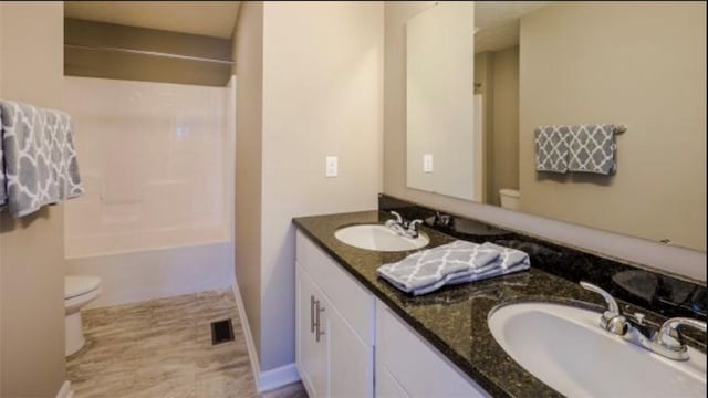 full bathroom featuring toilet, double vanity, and shower / bathtub combination