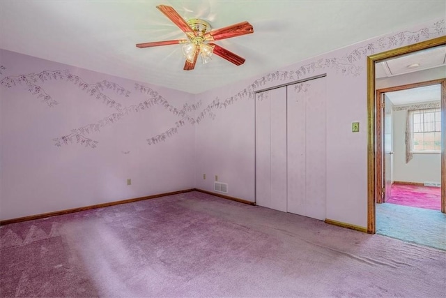 unfurnished room featuring carpet floors, attic access, a ceiling fan, and baseboards