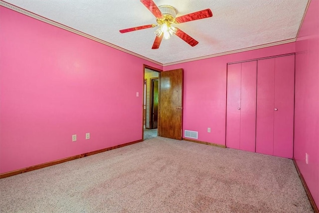 unfurnished bedroom featuring carpet, a textured ceiling, a closet, baseboards, and a ceiling fan