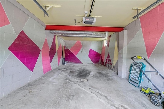 garage with a garage door opener and concrete block wall