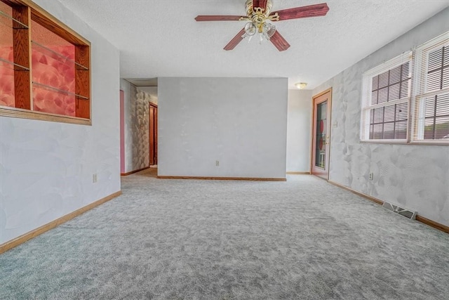 carpeted spare room featuring ceiling fan, a textured ceiling, and baseboards