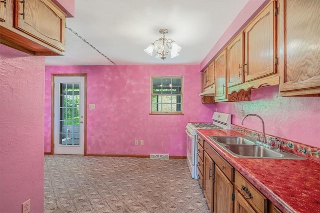 kitchen with white gas range, a sink, healthy amount of natural light, a chandelier, and a textured wall
