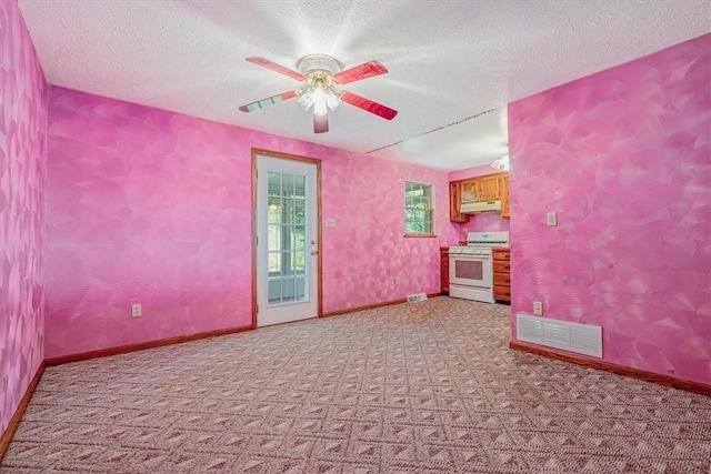empty room featuring light colored carpet, ceiling fan, a textured ceiling, and baseboards