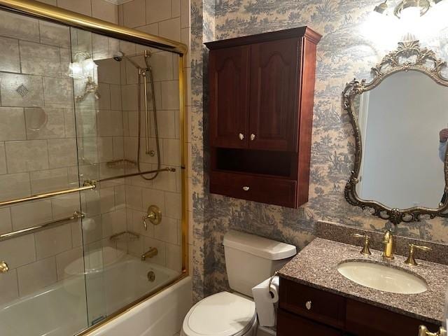 bathroom with wallpapered walls, toilet, combined bath / shower with glass door, and vanity
