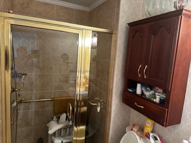 bathroom with crown molding, a shower stall, and toilet