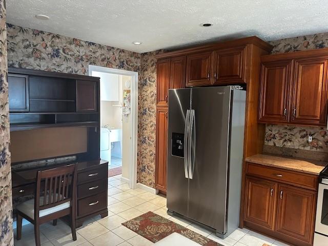 kitchen with stainless steel refrigerator with ice dispenser, wallpapered walls, a textured ceiling, light tile patterned floors, and open shelves
