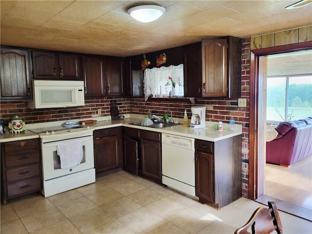 kitchen with white appliances, a sink, light countertops, and dark brown cabinetry