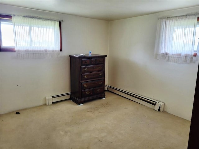 spare room featuring baseboard heating and light carpet