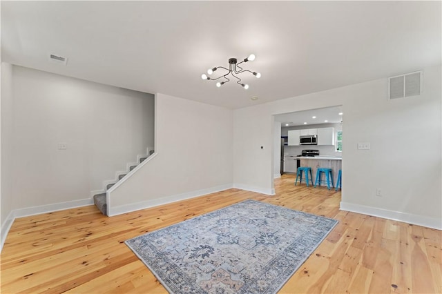23 Saint Thomas St, South Side, PA 15203 - unfurnished living room featuring a chandelier, light wood-type flooring, stairs, and baseboards