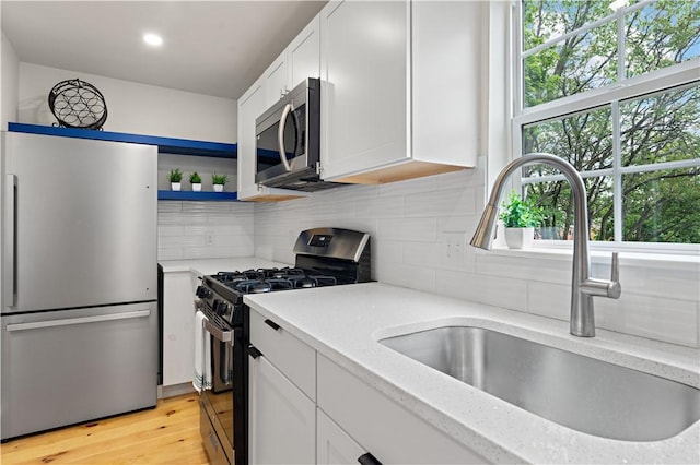 23 Saint Thomas St, South Side, PA 15203 - kitchen featuring stainless steel appliances, a sink, white cabinetry, tasteful backsplash, and light wood finished floors