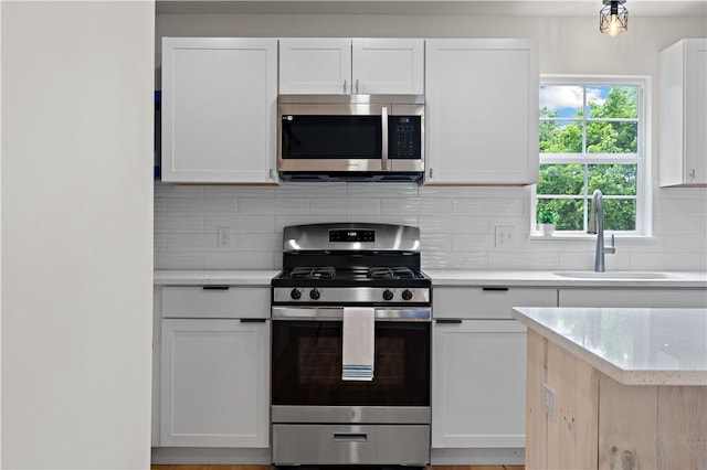 23 Saint Thomas St, South Side, PA 15203 - kitchen with stainless steel appliances, a sink, tasteful backsplash, white cabinets, and light stone counters